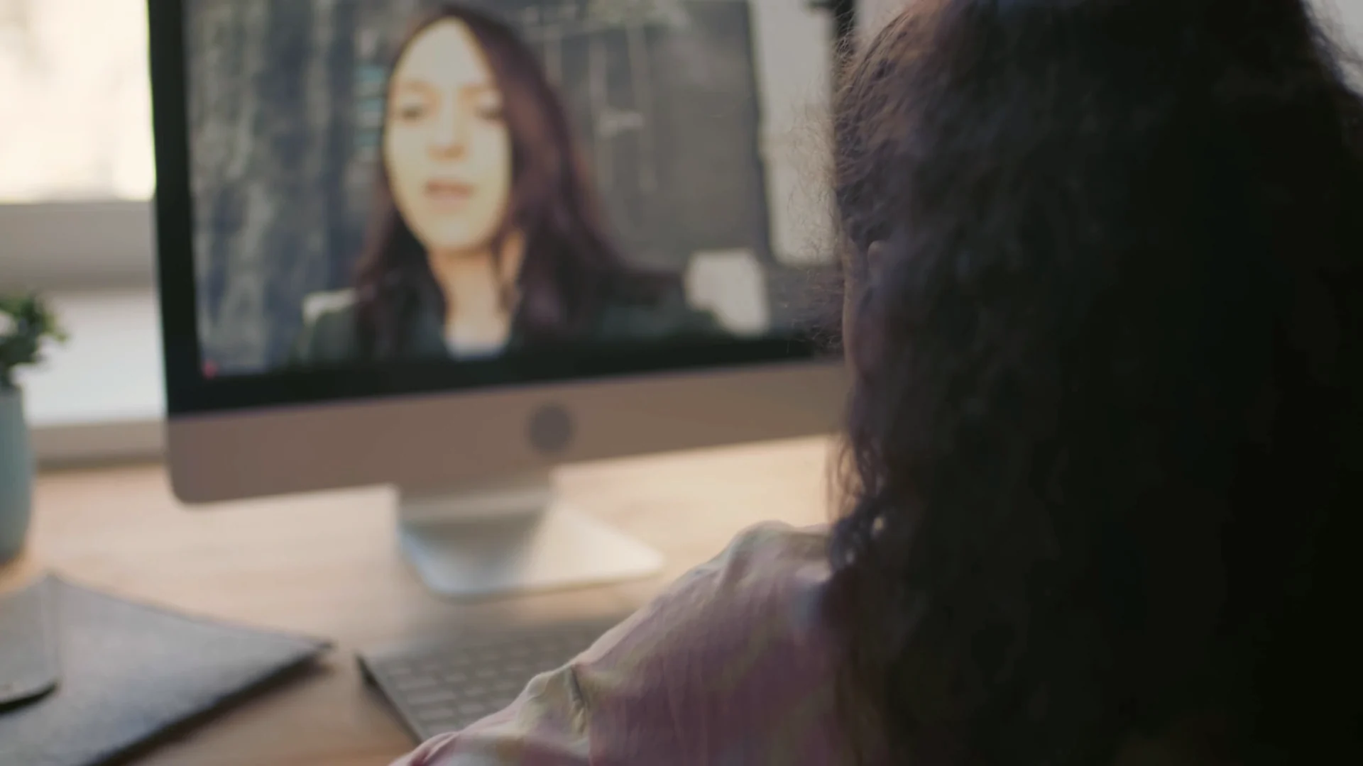A girl at home in a live one-to-one lesson, her teacher on the screen in front of her