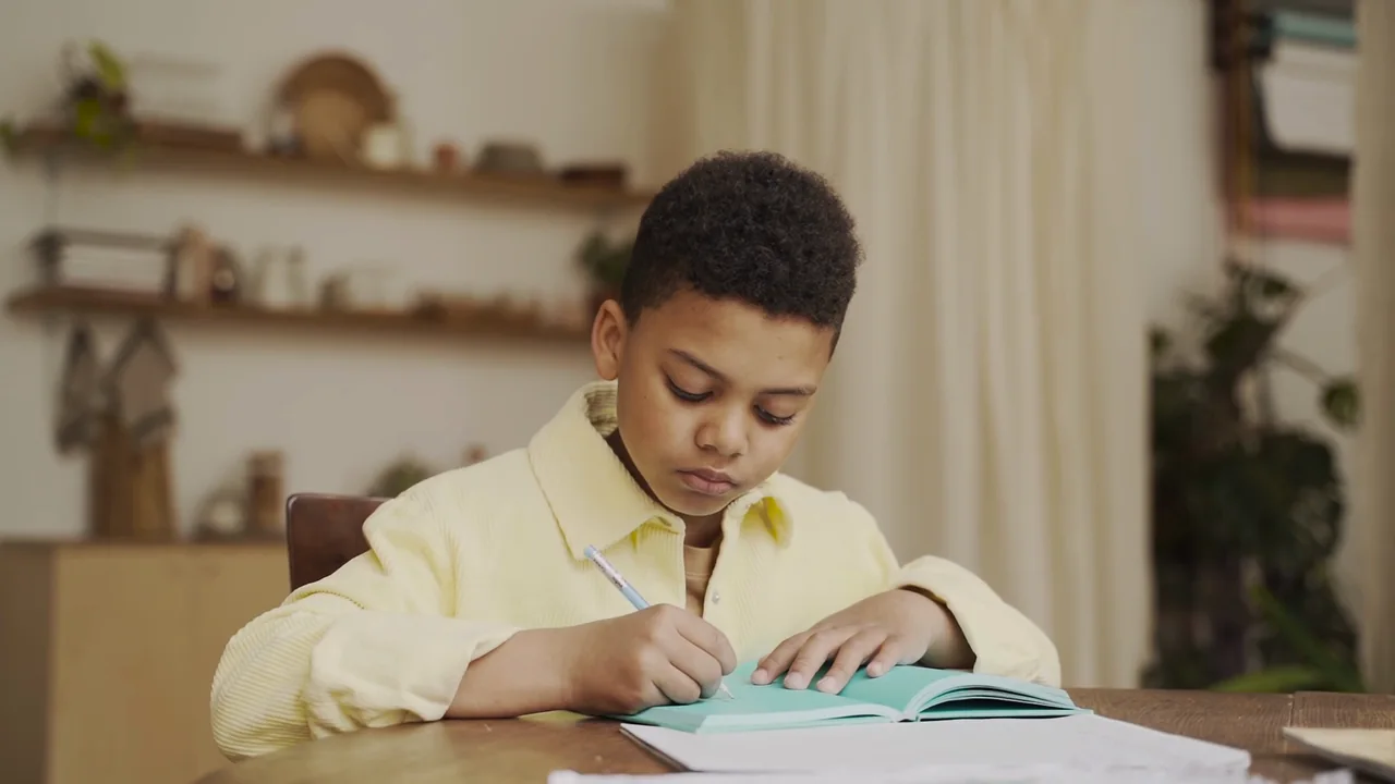 A boy smiling as he works through his homework